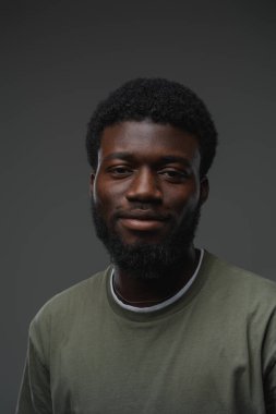 Afrikalı etnik bir adamın gri arka planda günlük kıyafetler giydiği bir stüdyo fotoğrafı..