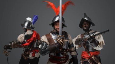 Shot of medieval conquistador staring at camera with two comrades on his sides. clipart