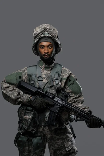 Natoの制服とヘルメットの暗い肌の兵士は プレイングレーの背景に深刻な表現でポーズ — ストック写真