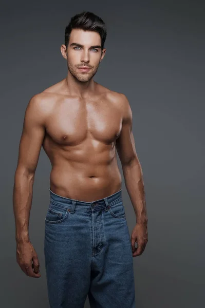 セクシーなとカリスマブルネット男性モデルとともに裸胴とジーンズ グレーの背景 — ストック写真