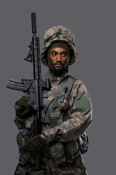 Natoの制服とヘルメットの暗い肌の兵士は プレイングレーの背景に深刻な表現でポーズ — ストック写真