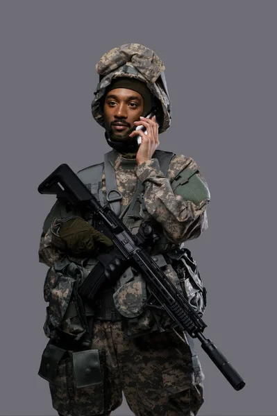 一名身穿制服 头戴头盔的年轻军人微笑着在电话中交谈 显示出身着制服的士兵的沟通技巧 — 图库照片