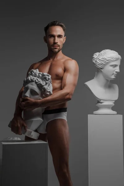 男模一种只穿内裤的有诱惑力的男模 摆出古希腊半身像 紧贴着他的身体 背景灰白 — 图库照片