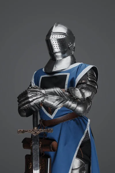 鎧を着た中世の警備員と剣を持った青いコート像のポーズで立って灰色の背景を背景に — ストック写真