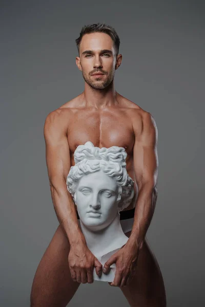 彼の体に対して押された古代ギリシャのバスト彫刻とポーズをとって 灰色の背景を背景に設定 — ストック写真