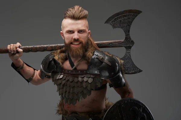 Intimidating bearded Viking wearing furs and light armor, gripping an axe on a gray background