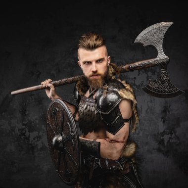 Kürk ve hafif zırhlı sakallı bir Viking 'in çarpıcı bir görüntüsü. Güçlü bir balta ve kalkan taşıyor.