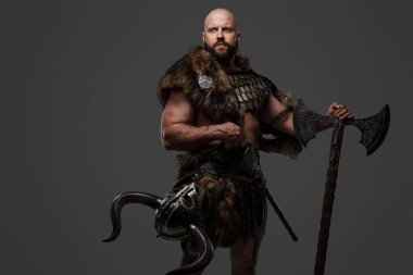 Kel, sakallı bir Viking kürk ve hafif zırh giyiyor, büyük bir balta taşıyor, tarafsız bir arkaplana karşı.