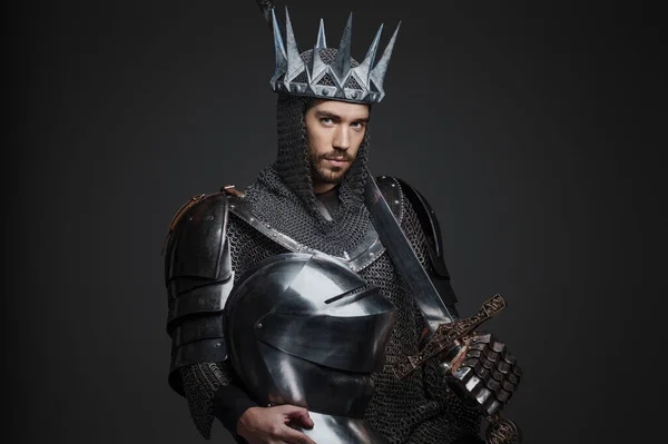 重い鎧 チェーンメール スチールクラウンでハンサムな王の肖像画 灰色の背景に対して剣でポーズ — ストック写真