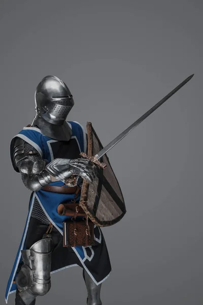 Синий Рыцарь Средневековом Плаще Активно Размахивает Мечом Битве Сером Фоне — стоковое фото