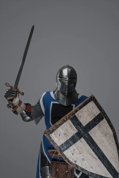 青のコートを着て中世の騎士積極的に灰色の背景に戦いで剣をスイング — ストック写真