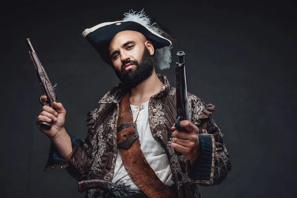 海盗一个黑胡子海盗 拿着两支火枪 身穿背心 头戴帽子 靠着黑暗的纹理墙 — 图库照片