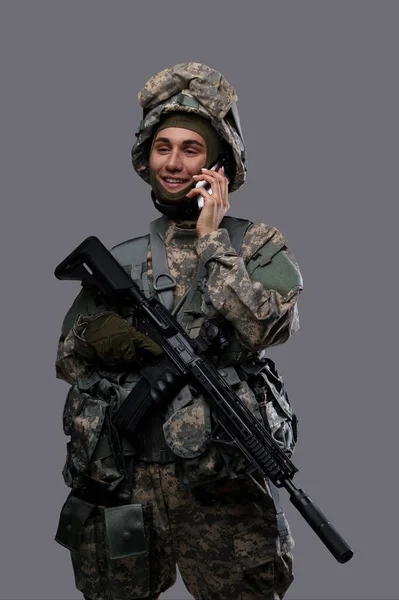 Soldado Uniforme Capacete Sorri Ter Uma Conversa Telefônica Fundo Cinza — Fotografia de Stock
