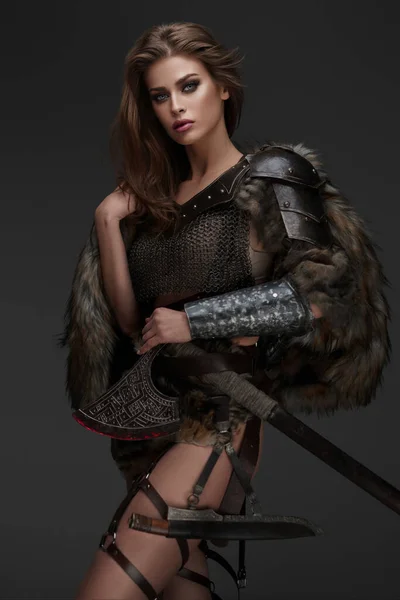 一个迷人的维京主题模特 身穿链甲和毛皮 拿着一把灰色背景的斧头 — 图库照片