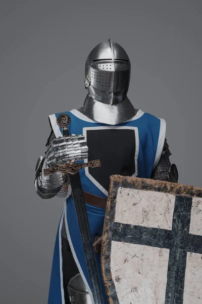 青のコートを着た中世の騎士で剣と盾を灰色の背景に — ストック写真