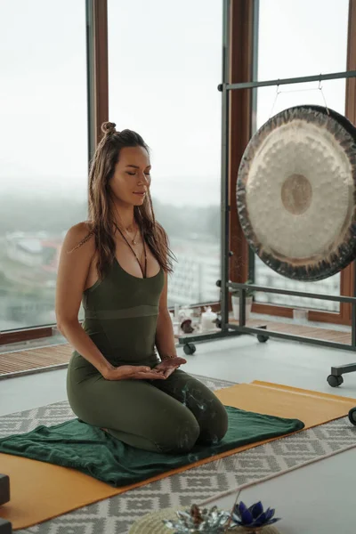 Mujer Ropa Deportiva Verde Practicando Yoga Meditación Contra Ventanas Panorámicas — Foto de Stock