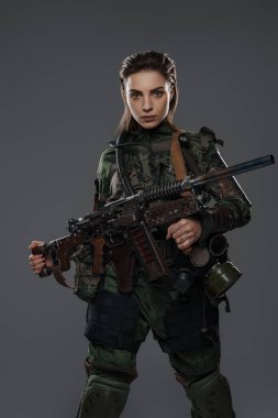 Bir kadın askerin portresi. Elinde ev yapımı otomatik bir tüfek var. Gri bir arka plana karşı Orta Doğu çatışmasında bir isyancıyı ya da partizanı tasvir ediyor.