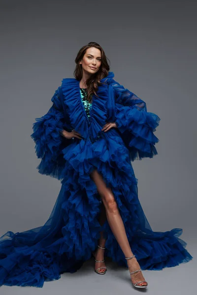一个迷人的模特 穿着华丽的蓝色狂欢节礼服 在灰色的背景下摆出迷人的笑容 — 图库照片
