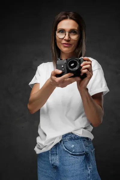 Radostná Fotografka Brýlích Bílém Tričku Fotoaparátem Zasazená Náladovém Pozadí — Stock fotografie