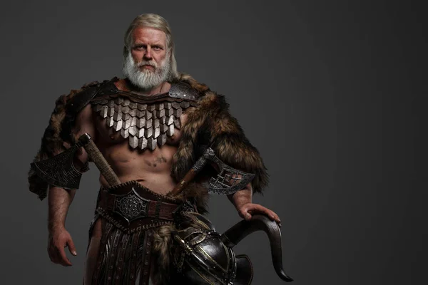 Grizzled elderly Viking warrior displaying strength and wisdom clad in furs and light armor, with a helmet slung on his waist on a neutral background