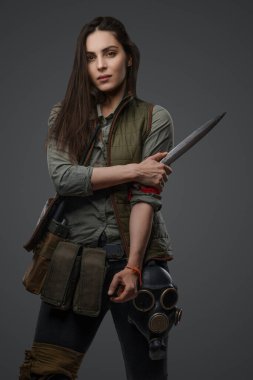 Middle Eastern descent in post-apocalyptic survival gear, brandishing a dagger on a gray backdrop, showcasing her determination to survive clipart