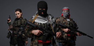Orta Doğu 'dan radikal radikallerin üçlüsü kamuflaj, keffiyeh ve kar maskesi giyerek gri arka planda poz veriyorlar.