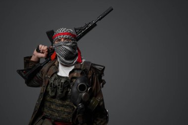 Orta Doğu radikal fanatik askeri beyaz keffiyeh ve kamuflajlı arazi üniforması giyiyordu. Gri bir arka plana karşı otomatik bir tüfeği vardı.
