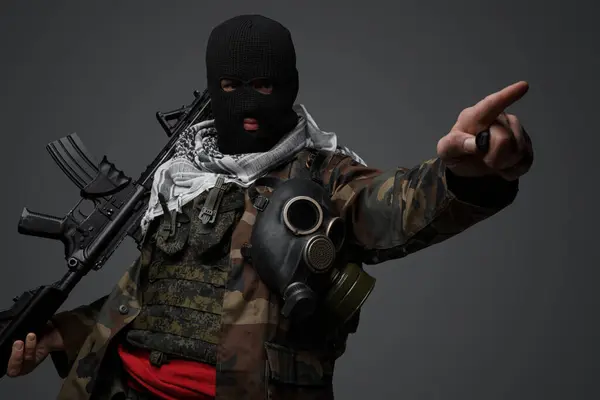 Middle Eastern radical fanatic soldier, clad in a black balaclava and camouflaged field uniform, armed with a rifle, pointing menacingly in a certain direction