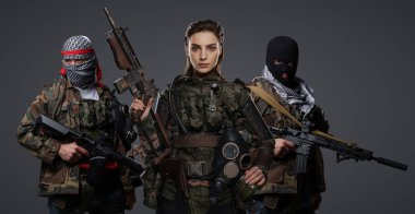 Üç Ortadoğulu militan grubu kamuflaj üniformaları, keffiyehler ve kar maskeleri giyip gri arka planda poz veriyorlar.