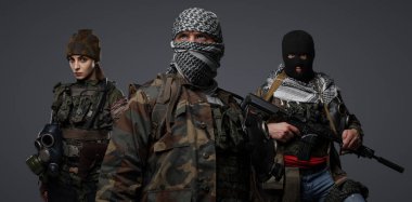 Orta Doğu 'dan radikal radikallerin üçlüsü kamuflaj, keffiyeh ve kar maskesi giyerek gri arka planda poz veriyorlar.