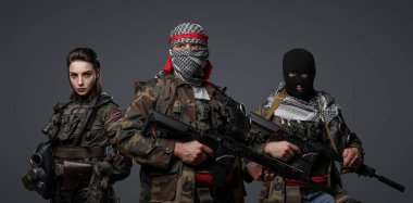 Group of three Middle Eastern militants dressed in camouflage uniforms, keffiyehs, and balaclavas posing against a gray background clipart