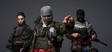 Orta Doğu 'dan radikal radikallerin üçlüsü kamuflaj, keffiyeh ve kar maskesi giyerek gri arka planda poz veriyorlar.