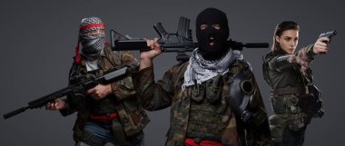 Orta Doğu 'dan radikal radikallerin üçlüsü kamuflaj, keffiyeh ve kar maskesi giyerek gri arka planda poz veriyorlar.