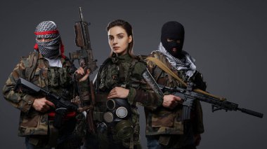Orta Doğu 'dan radikal radikallerin üçlüsü kamuflaj, keffiyeh ve kar maskesi giyerek gri arka planda poz veriyorlar.