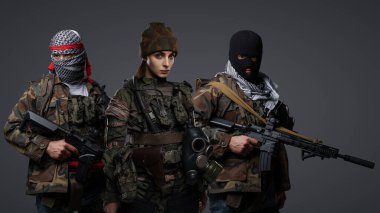 Üç Ortadoğulu militan grubu kamuflaj üniformaları, keffiyehler ve kar maskeleri giyip gri arka planda poz veriyorlar.