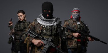 Üç Ortadoğulu militan grubu kamuflaj üniformaları, keffiyehler ve kar maskeleri giyip gri arka planda poz veriyorlar.