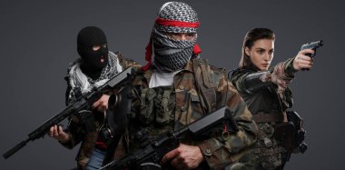 Orta Doğu 'dan radikal radikallerin üçlüsü kamuflaj, keffiyeh ve kar maskesi giyerek gri arka planda poz veriyorlar.
