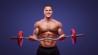 Canlı mor bir arka planda halterle gülümseyen formda bir adam.