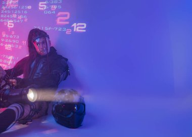 A female figure, dressed in a futuristic tactical black ensemble, reclines on the ground with a sizable projector against a backdrop of projected digital symbols clipart