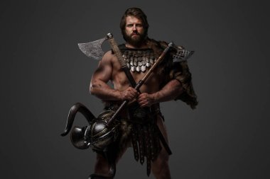 Kürk ve hafif zırhlı vahşi sakallı bir Viking savaşçısı, kemerine bağlı bir miğfer, gri arka planda büyük iki elli bir balta tutuyor.