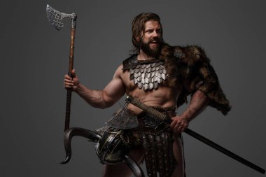 Kürk ve hafif zırhlı vahşi sakallı bir Viking savaşçısı, kemerine bağlı bir miğfer, gri arka planda büyük iki elli bir balta tutuyor.