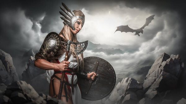 A valiant Valkyrie with a winged helmet stands in a dramatic mountainous terrain with a dragon flying in the stormy sky