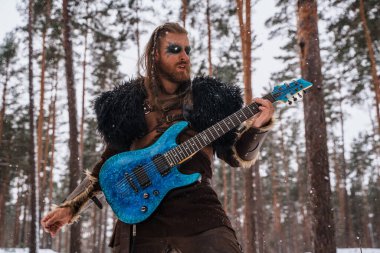 Vikinglerden esinlenilmiş bir müzisyen, karlı bir ormanda elektro gitar çalar, antik savaşçı ve modern müzik kültürünün bir birleşimini somutlaştırır.