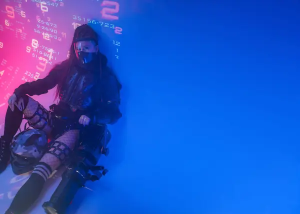 未来的な戦術的な黒いスーツの女性が床に横たわり オートバイのヘルメットと巨大なプロジェクターが彼女のそばに横たわり 予測されたデジタルシンボルを背景に — ストック写真