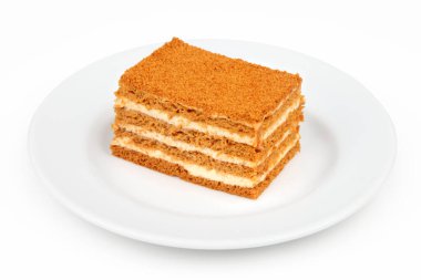 Beyaz arka planda izole edilmiş, bir tabakta bir parça ballı kek.