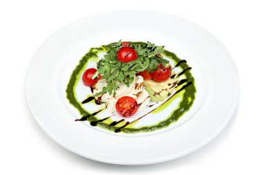 Kiraz domatesleri, roka ve mozzarella içeren, pesto sosu serpiştirilmiş, beyaz bir tabakta sunulan zarif gurme salatası.