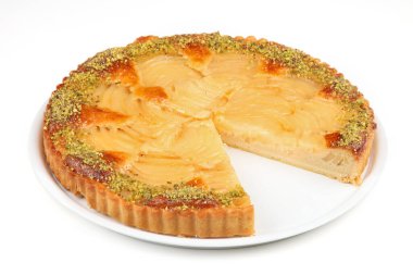 Fıstık kabuklu taze pişmiş elmalı tart, beyaz bir tabakta servis ediliyor, bir dilim kesilmiş..