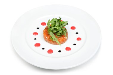 Taze roka ile kaplanmış zarif somon tartları, beyaz bir tabakta dekoratif sos noktaları ile güzelce sunuluyor..