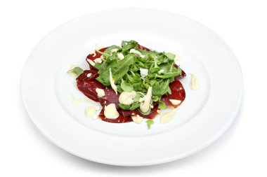 İnce et dilimleri, taze roka ve mayonez içeren bir gurme salata. Beyaz bir tabakta zarif bir şekilde sunuluyor..