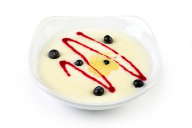 Taze böğürtlenlerle süslenmiş ve tatlı şurupla sulandırılmış, beyaz bir tabakta servis edilen bir kase kremalı irmik lapası..